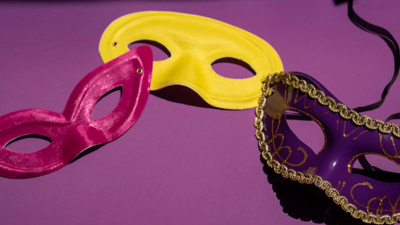 Colourful masquerade masks laid out on a purple background