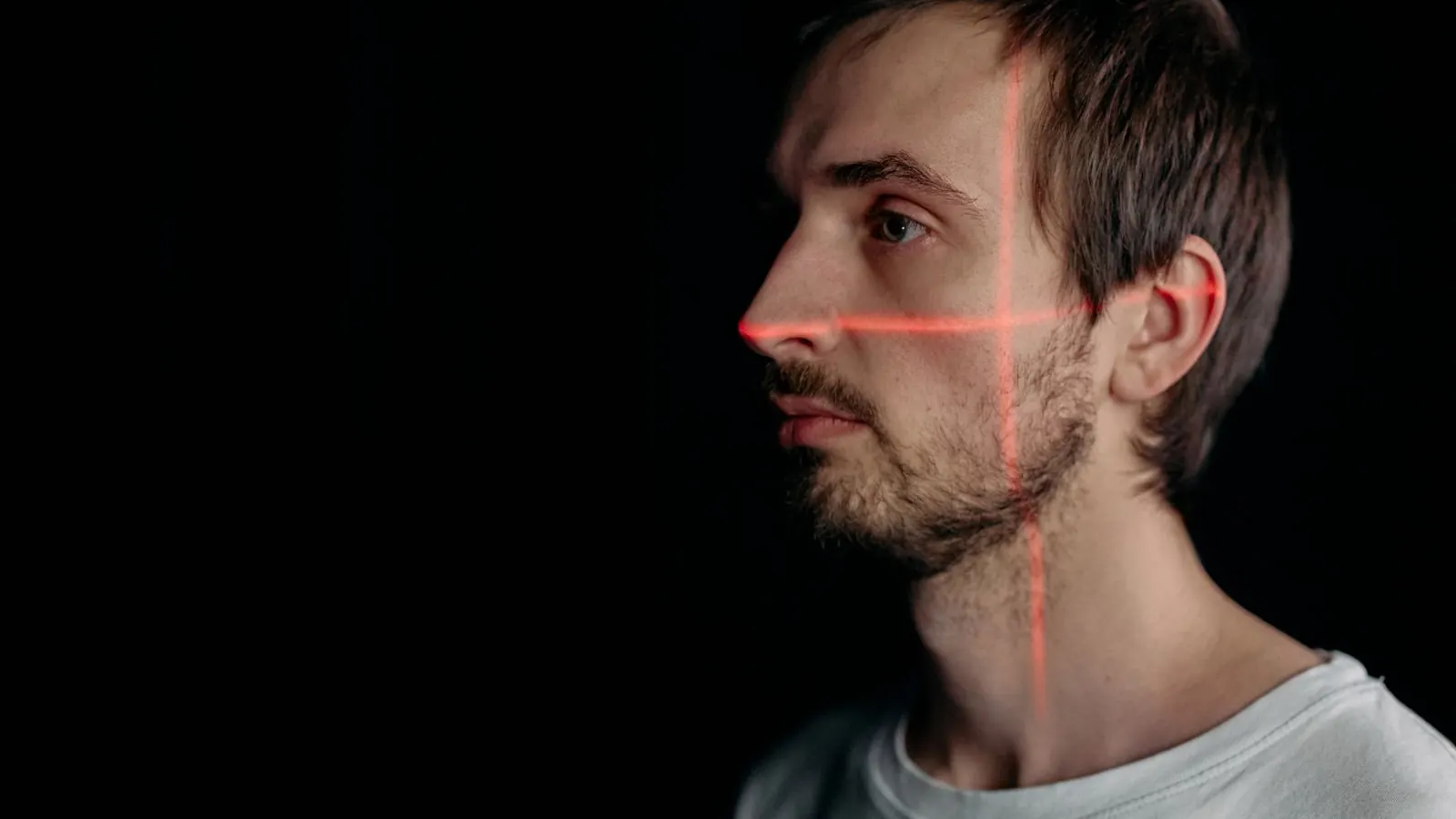 A man in profile with a laser grid projected on his face, like a facial age scan