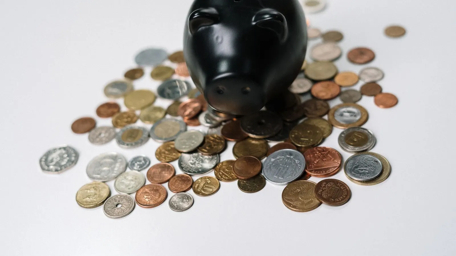 A black piggy bank surrounded by scattered coins