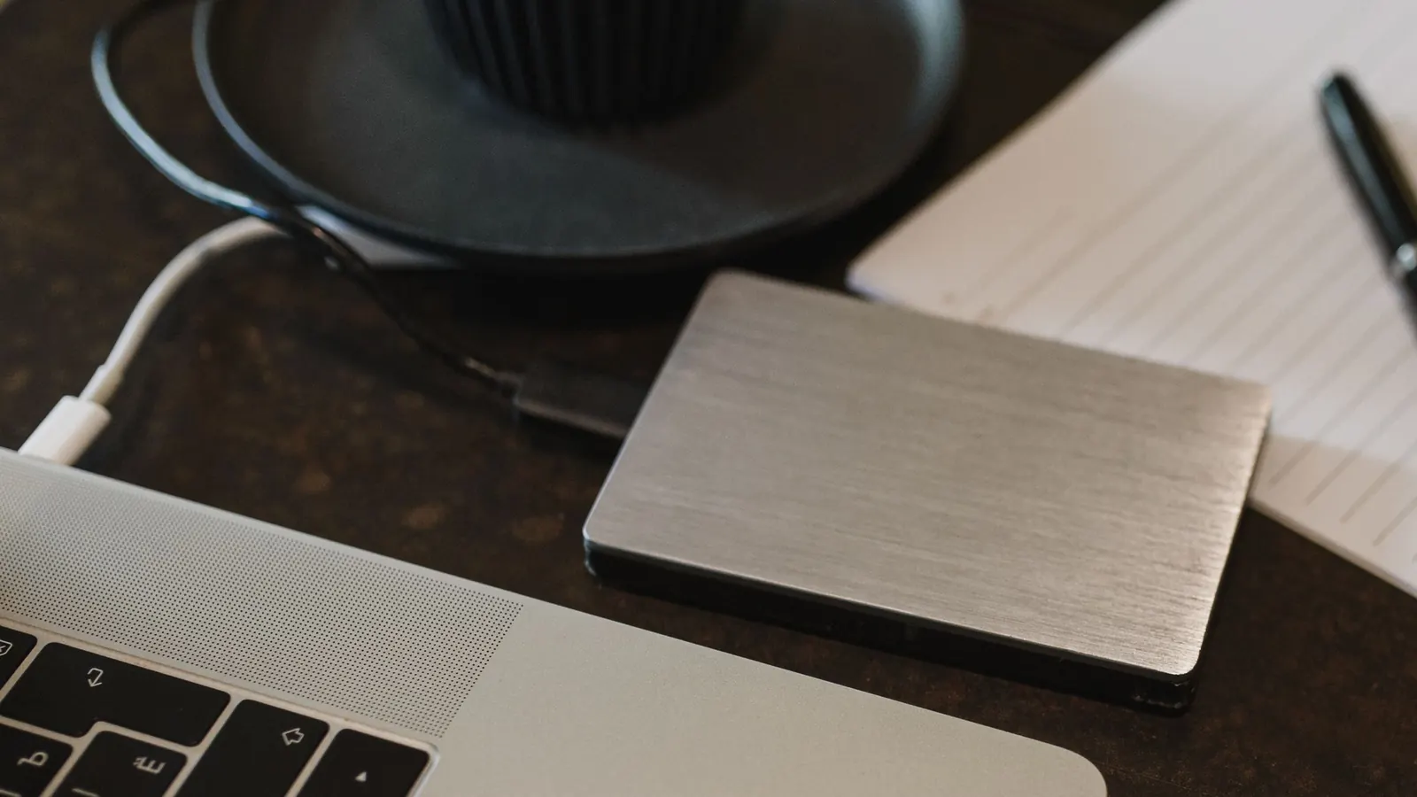 An external hard drive connected to a laptop by a USB cable on a desk