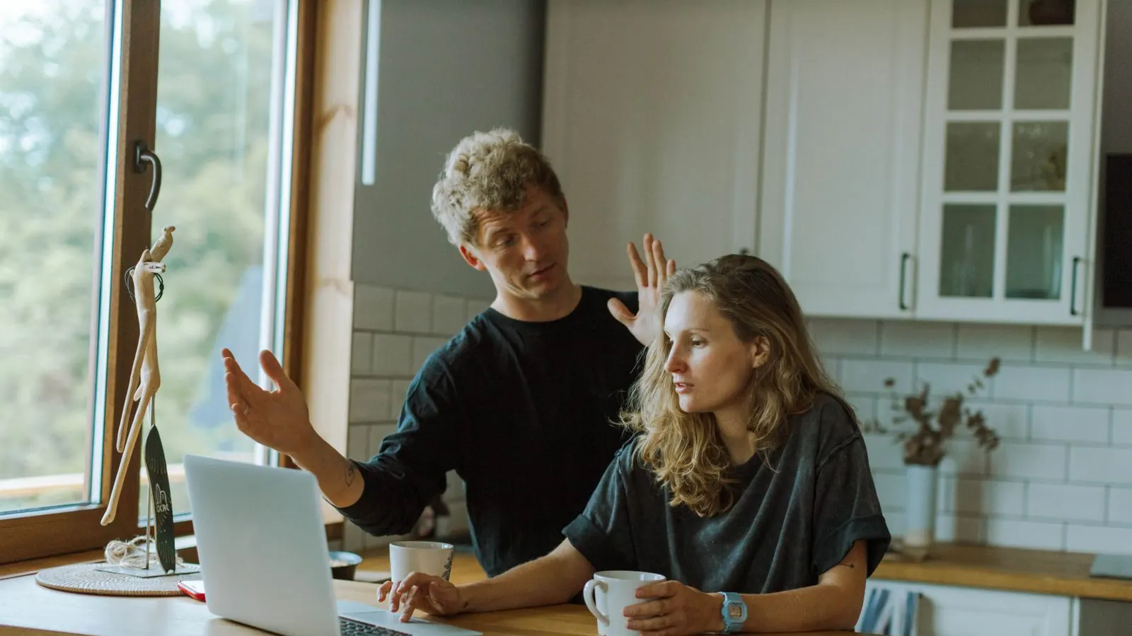 A couple talking over a laptop at a kitchen counter